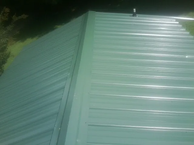New green metal panels meeting at the ridge of a roof — Flat Roof Repair work by our crew in Westernport