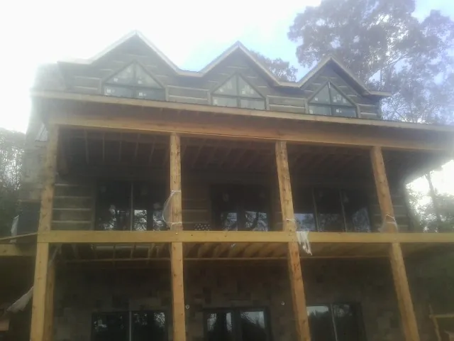 Dormers and porch framing on a large log home under construction — Roof Coating work by our crew in Westernport