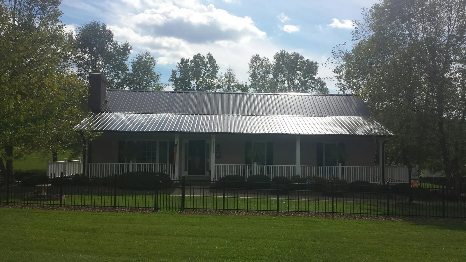 Gray metal roof on a brick ranch with a full width front porch — Gutter Guard Installation work by our crew in Westernport