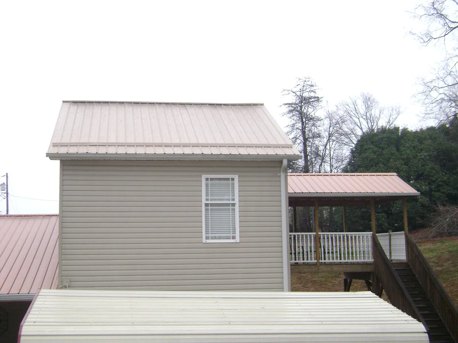 Tan metal roofs on a two story addition and attached porch, from a Roof Replacement job in Westernport