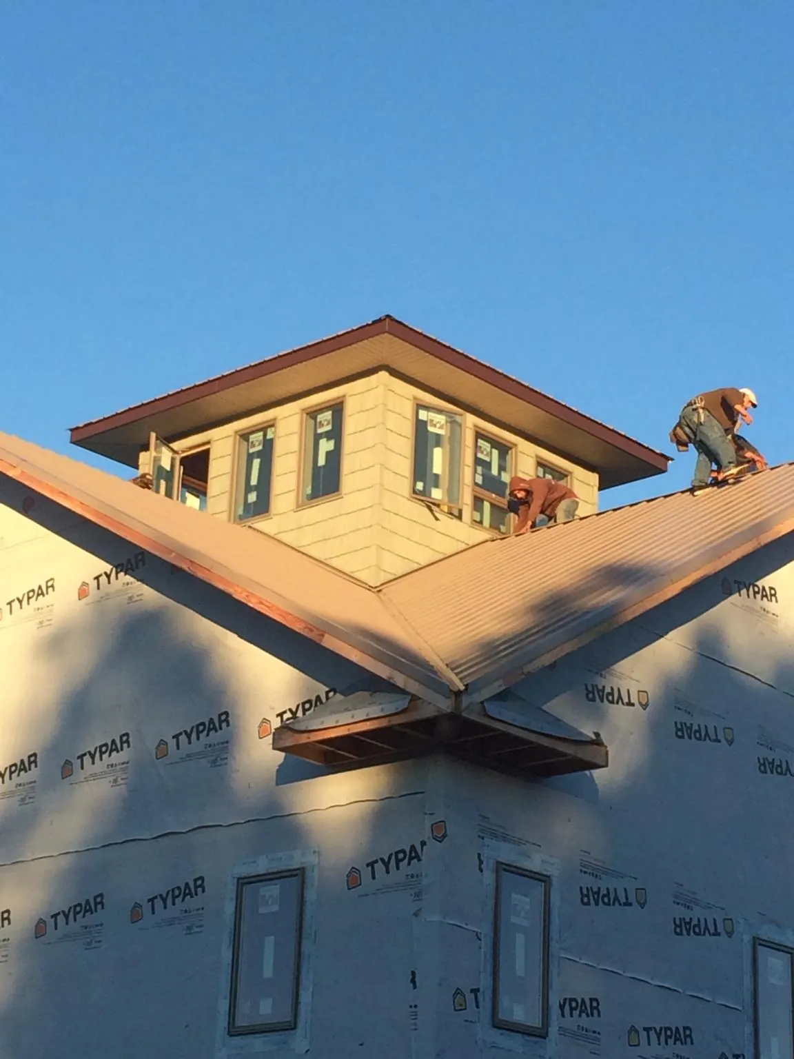 Roofers working around a rooftop cupola on a new metal roof at sunset — Roof Waterproofing in Westernport by Roofing Brothers